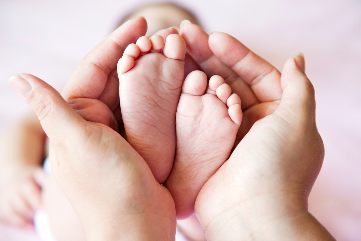 mother holding baby feet